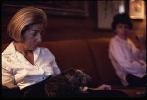 Middle-aged woman and her Yorkshire terrier seated on a sofa, a boy looks on
