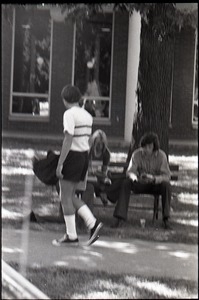 Young couple seated on park bench, reading copy of Free Spirit Press magazine (blurry)