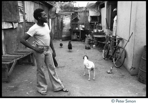 Jimmy Cliff standing in a dirt alleyway near his old home on Spanish Town Road