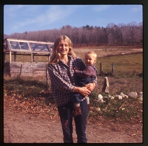 Janice Frey and baby Sequoya in front of a greenhouse, Montague Farm Commune