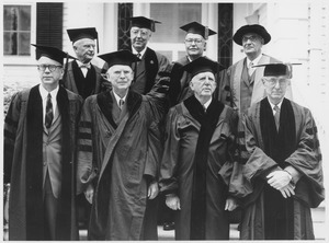 Eight men donning ceremonial gowns and caps