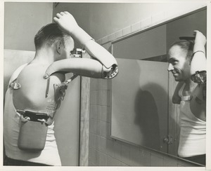 A man with a prosthetic arm device combs his hair