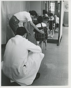 Doctor an physical therapist guiding young girl with artificial leg