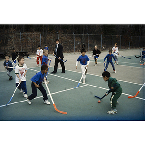 Field hockey game on an outdoor tennis court at the Eastern Middlesex Family YMCA