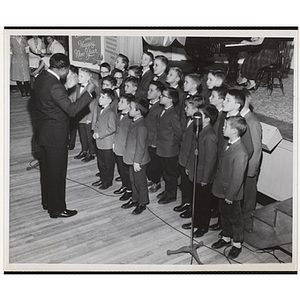 A man directs a boys' choir during a Christmas event