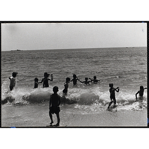 A group of children play in the surf on a beach