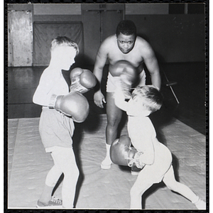 A boy lifts his arm to punch his boxing opponent in the South Boston gymnasium