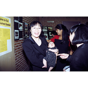Woman holds her baby near pictorial display at restaurant during Chinese Progressive Association's 20th Anniversary Celebration