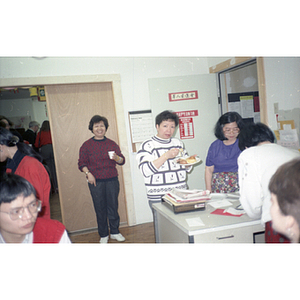 Woman holds a plate of food at the Chinese Progressive Association's office