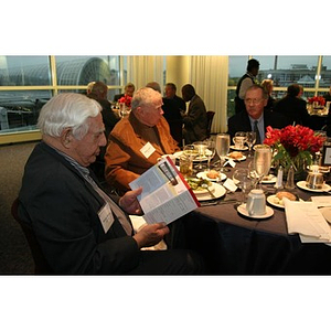 George Makris looks at a pamphlet about the Veterans Memorial during dinner