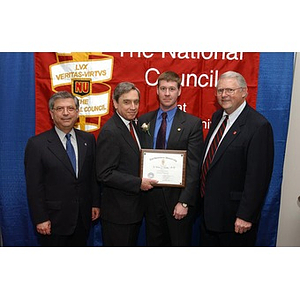 A new inductee poses with three men and his certificate at The National Council Dinner