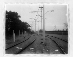 View of trolley tracks with workers in the distance