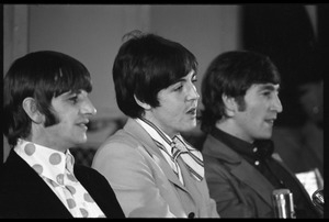 Ringo Starr, Paul McCartney, and John Lennon (l. to r.) seated at a table during a Beatles press conference