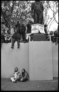 Vietnam Moratorium protesters perched on the wall beneath the statue of Jose Bonifacio de Andrada e Silva, Bryant Park, with antiwar signs from employees at Sports Illustrated and Fortune