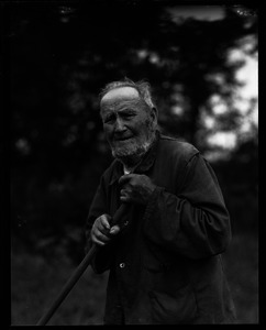 Older man, age 101, leaning on the handle of a hoe