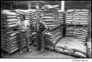 Managers in a stockroom at Erewhon Food Coop warehouse, Farnsworth Street, with bags on pallets (at right may be Tyler Smith, President of Erewhon)