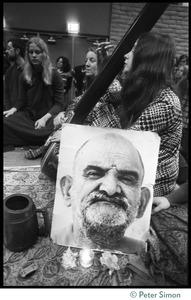 Musicians on stage with portrait of Neem Karoli Baba during an appearance by Ram Dass at the College of Marin