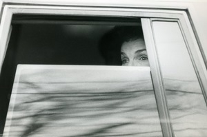 Jackie Onassis peering through a window of a limousine at the wedding of her niece Maria Shriver