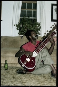 Bobby Davis (?) playing a sitar in a living room floor