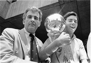 Unidentified boy holding NBA Championship trophy with unidentified man