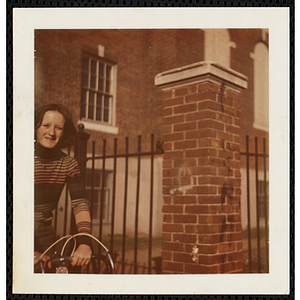 A girl from the South Boston Boys' Club riding a bicycle and looking at the camera