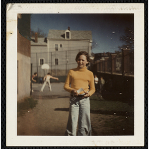 A girl, wearing a yellow turtleneck shirt, stands outside the South Boston Boys' Club building