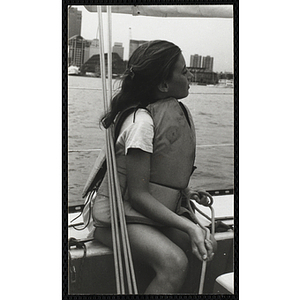 A girl sits on the deck of a sailboat in Boston Harbor