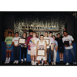 A group of children pose with trophies and certificates at an End of Year Party