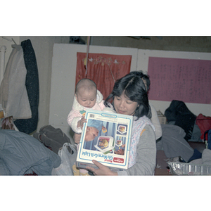 Woman holding baby and holiday gift at Chinese Progressive Association's Ninth Anniversary Celebration