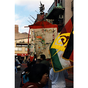 Man holds a banner while another man holds a Chinese Freemasons flag during a celebration of the Chinese New Year in Boston's Chinatown