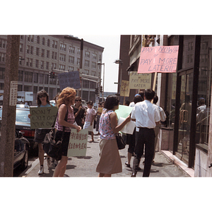 Demonstrators holdi protest signs and chant outside of Dynasty Restaurant in Chinatown as they picket for back wages for workers