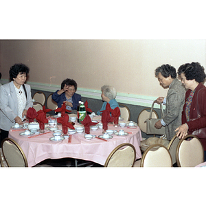 Guests stand around a restaurant table during Chinese Progressive Association's 15th Anniversary Celebration