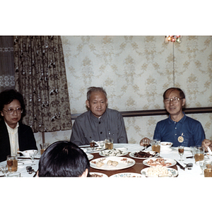 Henry Wong sits at a dinner table with others during a banquet