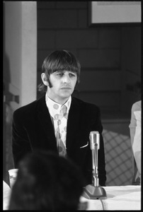 Ringo Starr seated in front of a microphone at a table, during a Beatles press conference