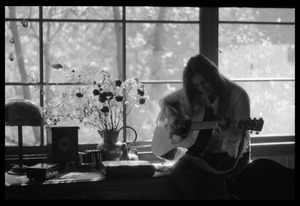 Judy Collins playing guitar while silhouetted against a window in Joni Mitchell's house in Laurel Canyon