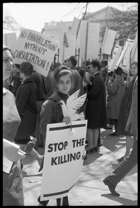 Woman holding a cutout cardboard peace dove and a sign reading 'Stop the killing', marching with antiwar demonstrators standing in front of the White House during the March on Washington