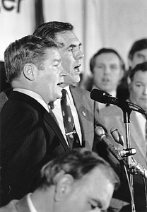 Mayor Raymond L. Flynn singing in a microphone with Massachusetts Senate President William M. Bulger