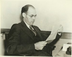 Clyde W. Dow sitting indoors, working behind desk