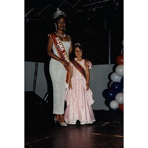 A woman and a young girl pose together wearing queen sashes and crowns at the Festival Puertorriqueño