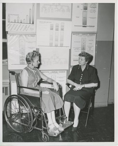 Two women, one in a wheelchair, in conversation at an administrators training group