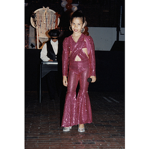 A girl in a pink sequined outfit stands with a microphone at the Festival Puertorriqueño