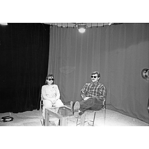 Two people wearing sunglasses on the set of Villa Victoria's public access television station.
