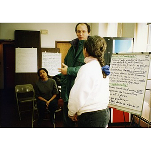 Man and woman talking in front of a large sheet of paper detailing methods of communication.