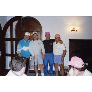 A four-man golf team posing for a picture as two men look on at a Boys & Girls Club Golf Tournament