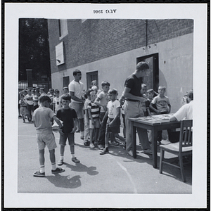 Boys standing in line at the registration table for a Boys' Club Freckle King Contest