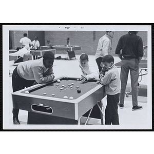 Three boys playing bumper pool in the game room