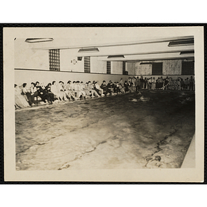 Swimmers race in a natorium pool as spectators look on