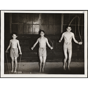 Two teenagers and a boy jump rope in a gymnasium