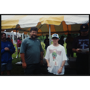 As Executive Director Jerry Steimel (far left) looks on, a man poses with a boy during the Battle of Bunker Hill Road Race