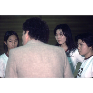 Female volleyball team stands in a huddle with their coach during a match